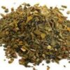 A pile of green tea leaves on top of a white surface.
